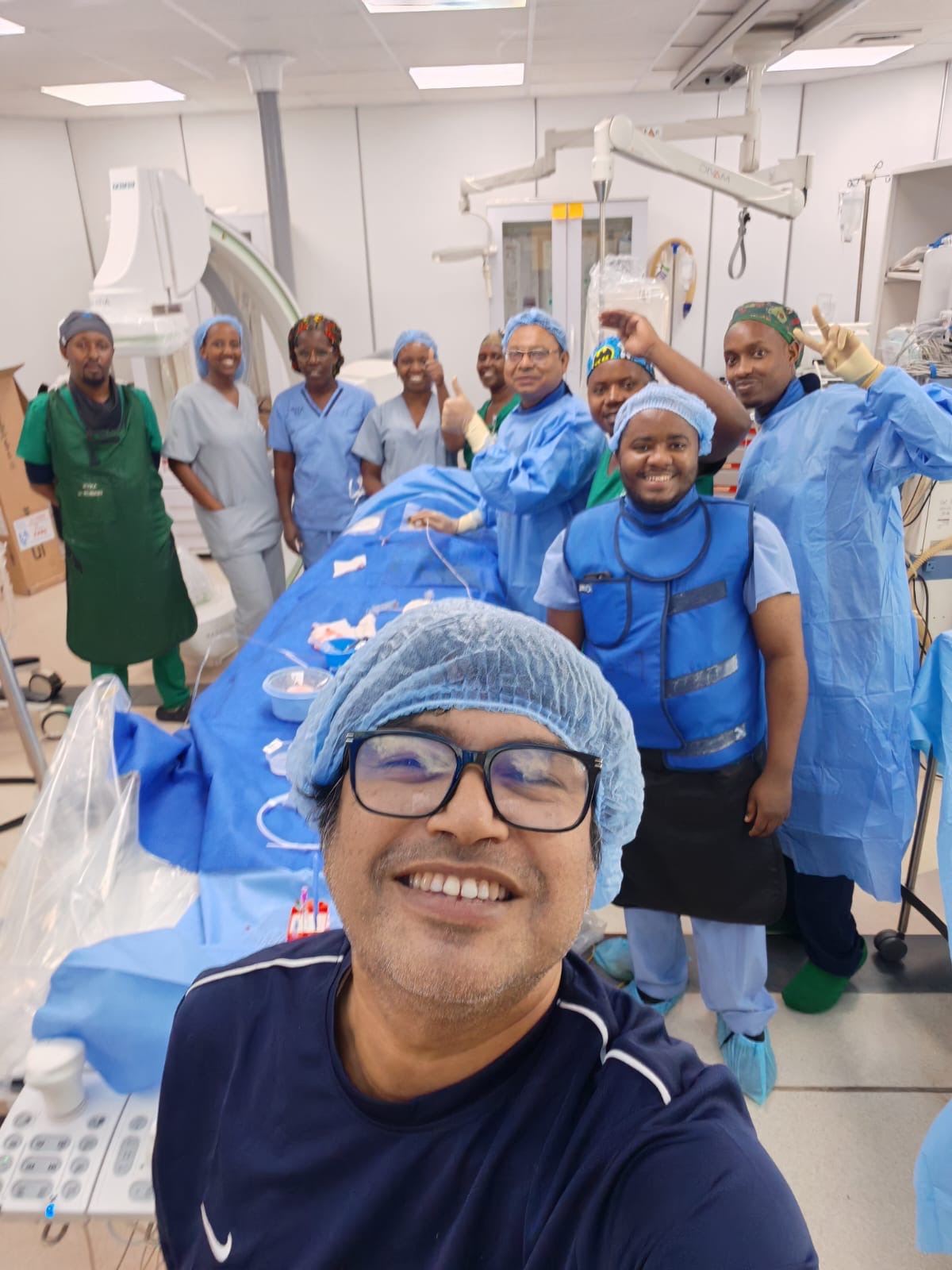 Clinical team members in surgical caps, gowns and lead aprons posing in a cardiac catheterization laboratory