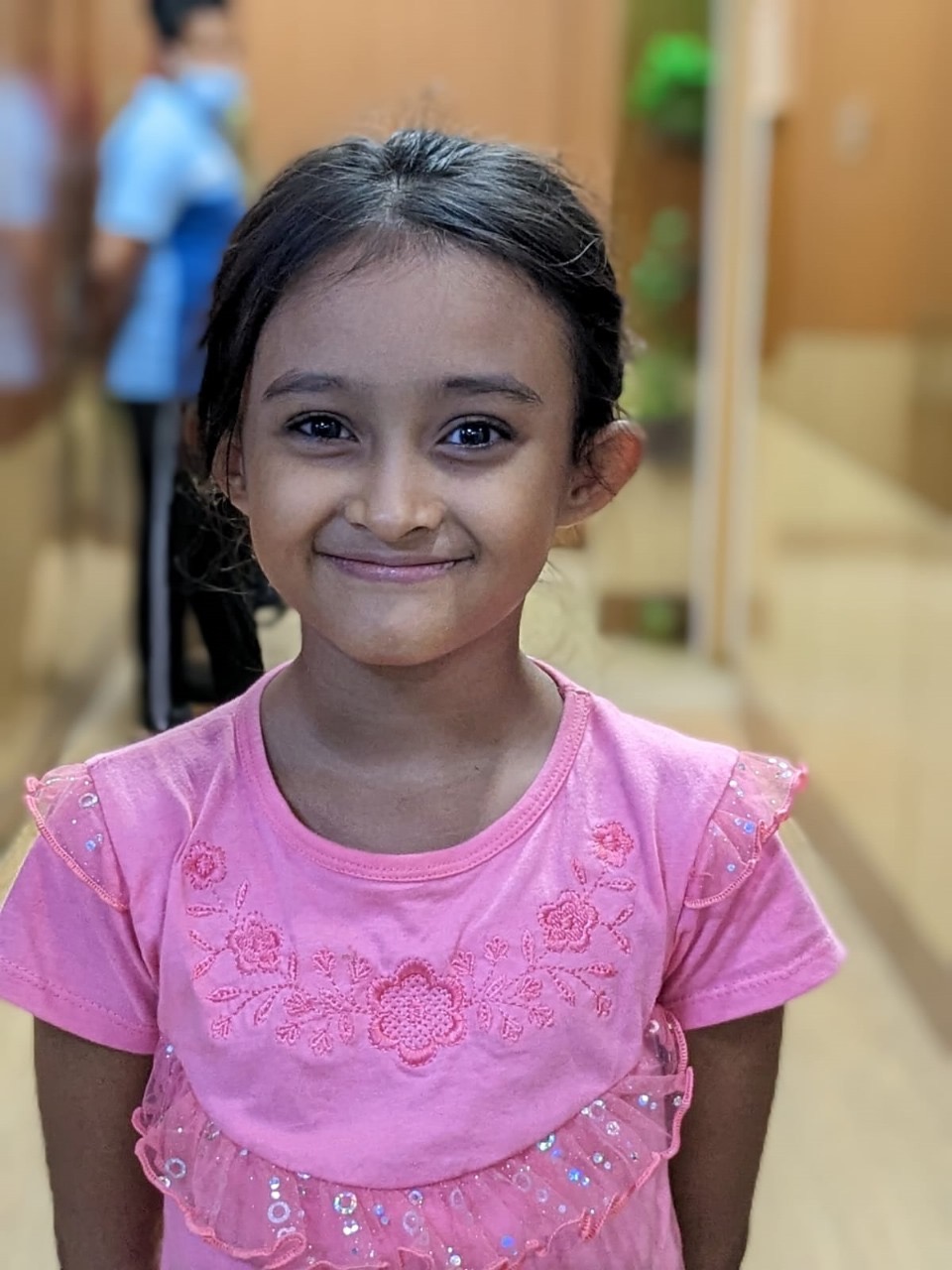 Smiling girl in a pink shirt in a hospital hallway